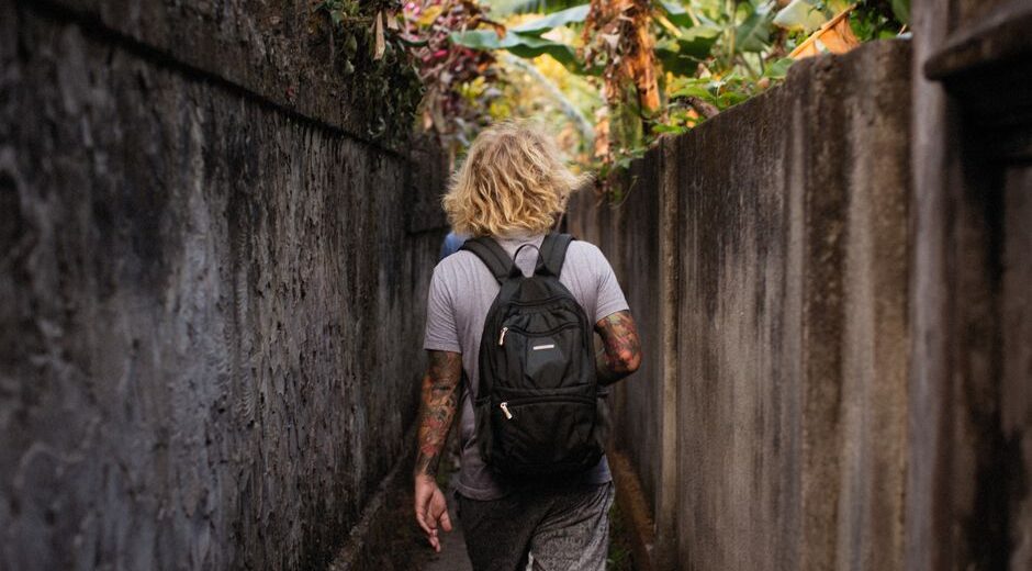 A small, sleek backpack with multiple visible compartments, standing on an urban street, suggesting efficient storage for daily life.