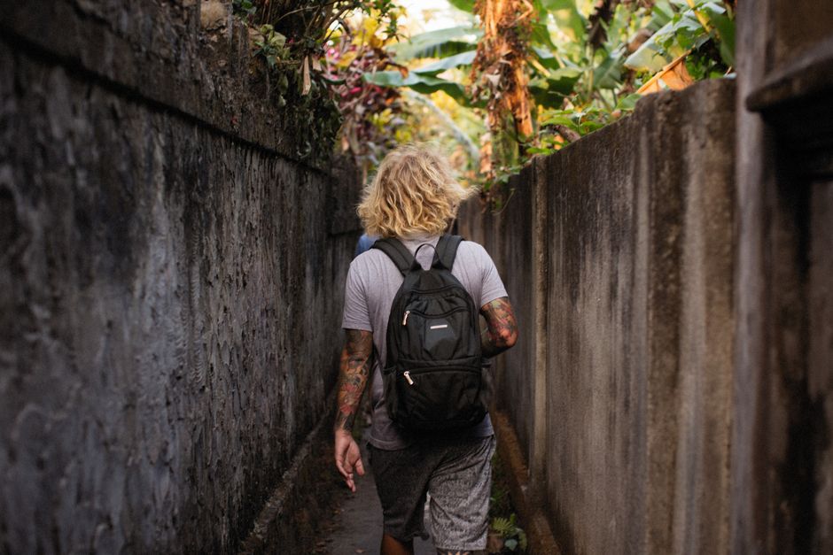 A small, sleek backpack with multiple visible compartments, standing on an urban street, suggesting efficient storage for daily life.