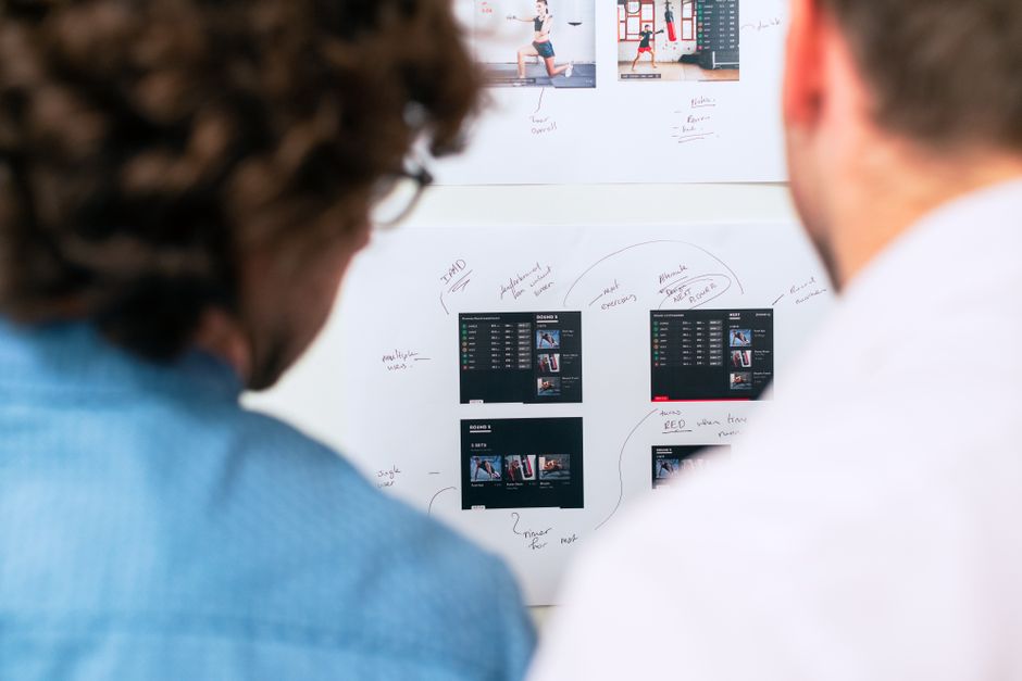 A small, diverse team of professionals collaboratively working on laptops, with a holographic AI interface projecting from a tablet showing data and tasks.