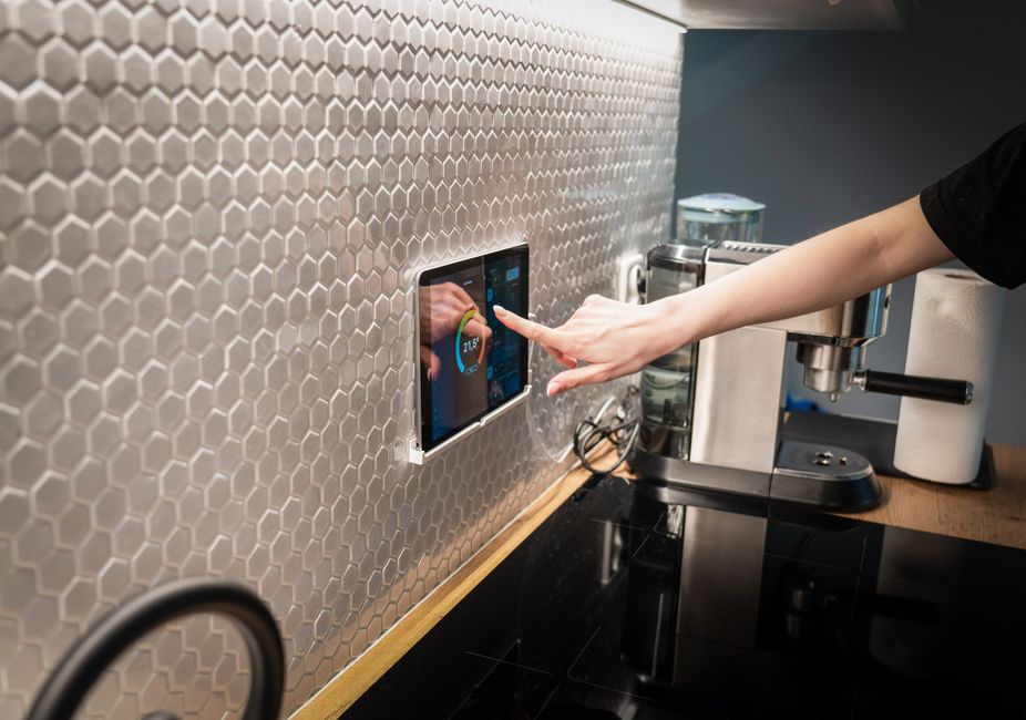 A hand interacting with a smart home control panel displaying various device statuses and settings, representing technology and digital tools for home management.