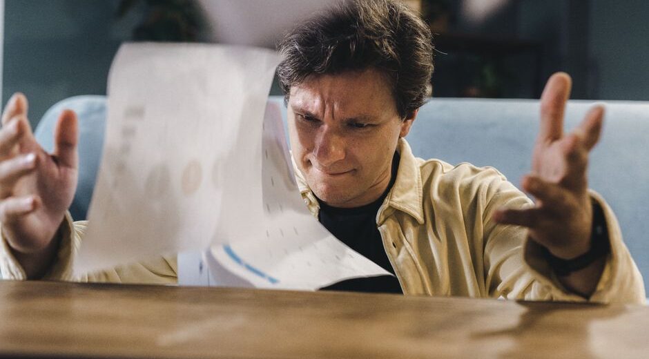 A person looking stressed and overwhelmed by a complex, dense spreadsheet on a laptop screen, symbolizing the limitations of manual data management.