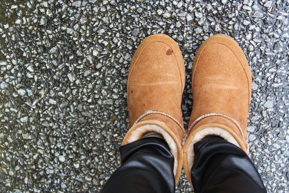 A pair of elegant, well-maintained leather winter boots resting beside a warm, crackling fireplace, suggesting comfort and style after a cold day.