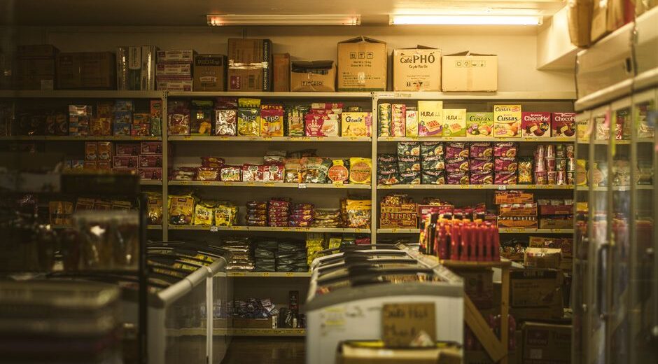 A shopper navigating a bright supermarket aisle filled with various packaged meals, highlighting the vast array of choices available.