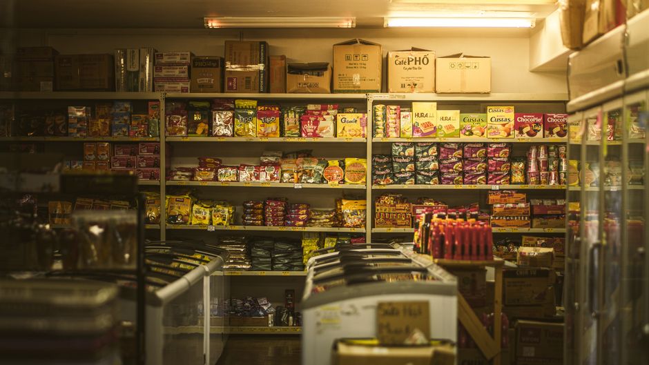 A shopper navigating a bright supermarket aisle filled with various packaged meals, highlighting the vast array of choices available.