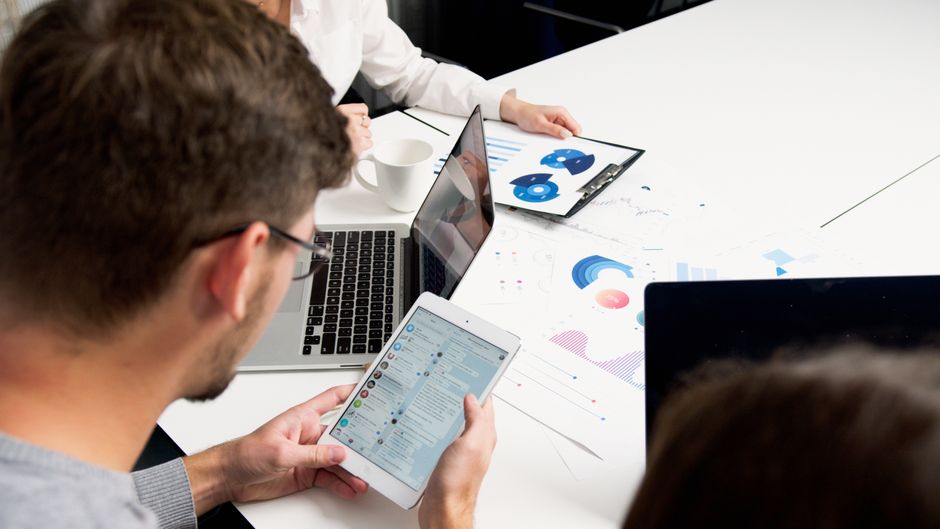 A small team collaborating around a desk, looking at a shared screen displaying CRM data and project management tools, fostering efficient workflow.
