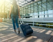 A traveler carefully measuring a soft-sided backpack with a tape measure to ensure it meets budget airline personal item dimensions.