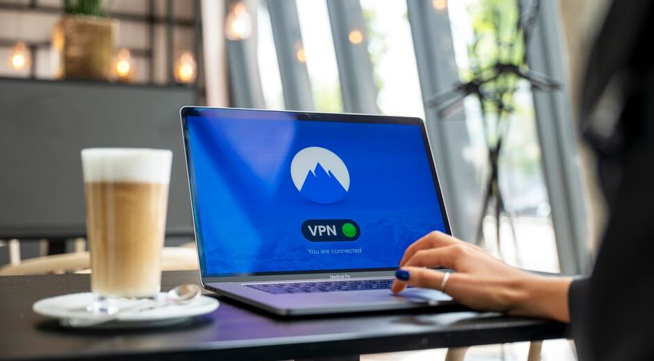 A traveler using a laptop in a cafe, with a digital padlock overlay symbolizing VPN security on public Wi-Fi.