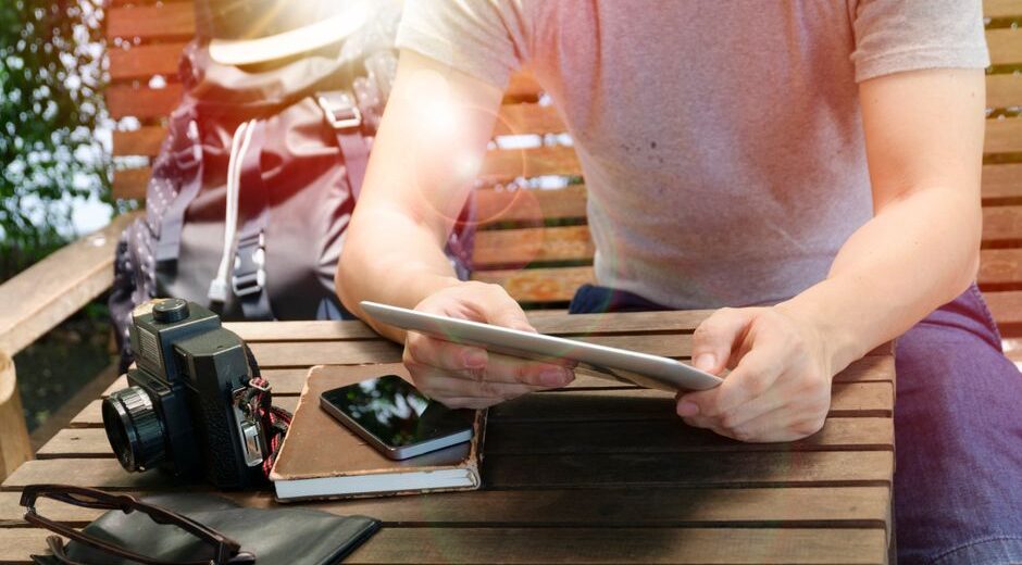 A person thoughtfully reviewing a travel insurance policy on a digital tablet, with a blurred map in the background, symbolizing careful planning.