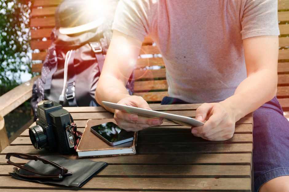 A person thoughtfully reviewing a travel insurance policy on a digital tablet, with a blurred map in the background, symbolizing careful planning.