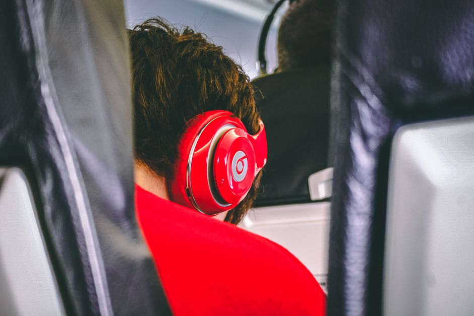 A person on an airplane, looking relaxed and wearing modern noise-cancelling headphones, while looking out the window.