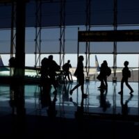 A person with a carry-on suitcase effortlessly navigating a busy European airport terminal, highlighting ease of travel.