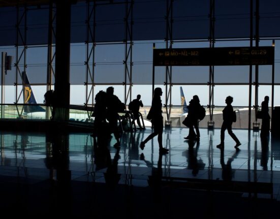 A person with a carry-on suitcase effortlessly navigating a busy European airport terminal, highlighting ease of travel.