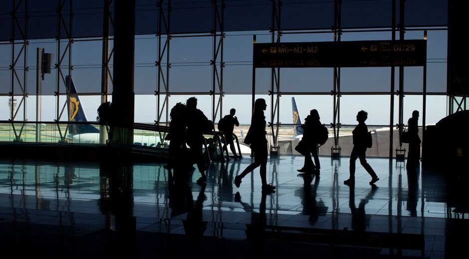 A person with a carry-on suitcase effortlessly navigating a busy European airport terminal, highlighting ease of travel.