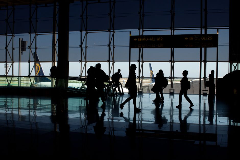 A person with a carry-on suitcase effortlessly navigating a busy European airport terminal, highlighting ease of travel.