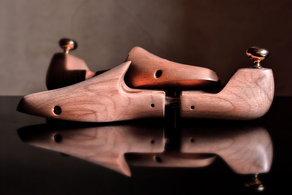 An assortment of shoe care items including wooden shoe stretchers, leather conditioner, and thick socks, arranged on a surface.