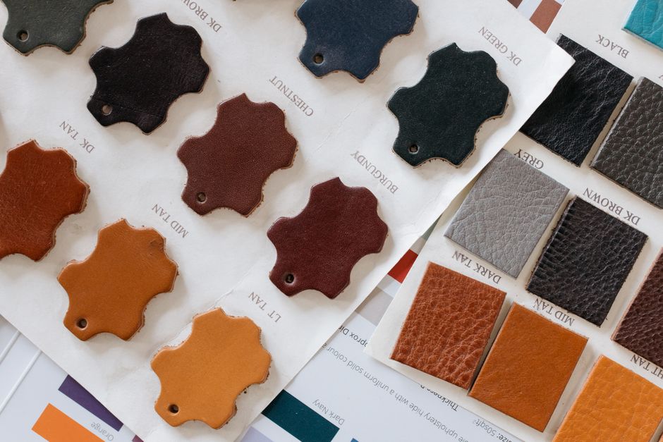 Close-up comparison of different material samples: rich brown real leather, sleek black PU vegan leather, and textured plant-based vegan leather.
