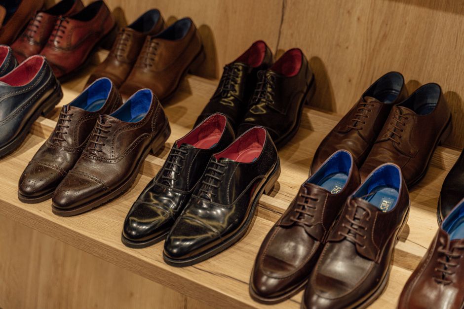 A diverse collection of men's office shoes, including Oxfords, Derbies, and Loafers, displayed neatly on a shelf.