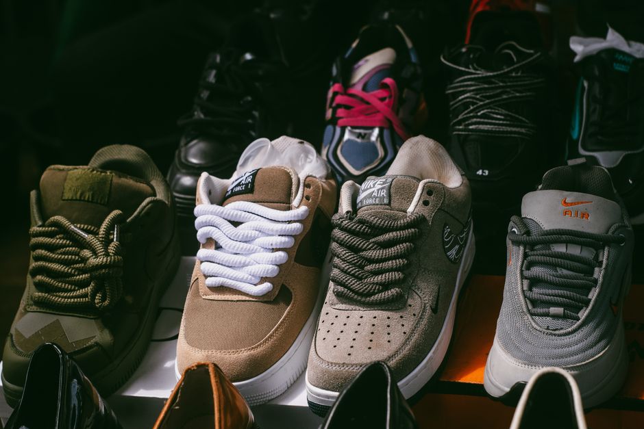 An array of different walking shoe styles and brands, including sneakers and boots, displayed on a shelf, highlighting choices for comfortable travel footwear.