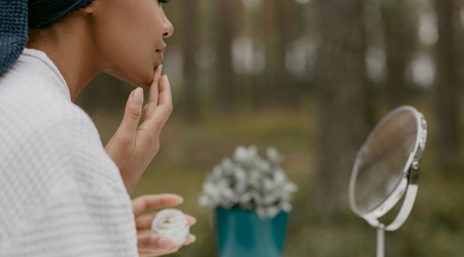 Woman gently applying moisturizer to her face in the morning, focusing on a healthy skin barrier.
