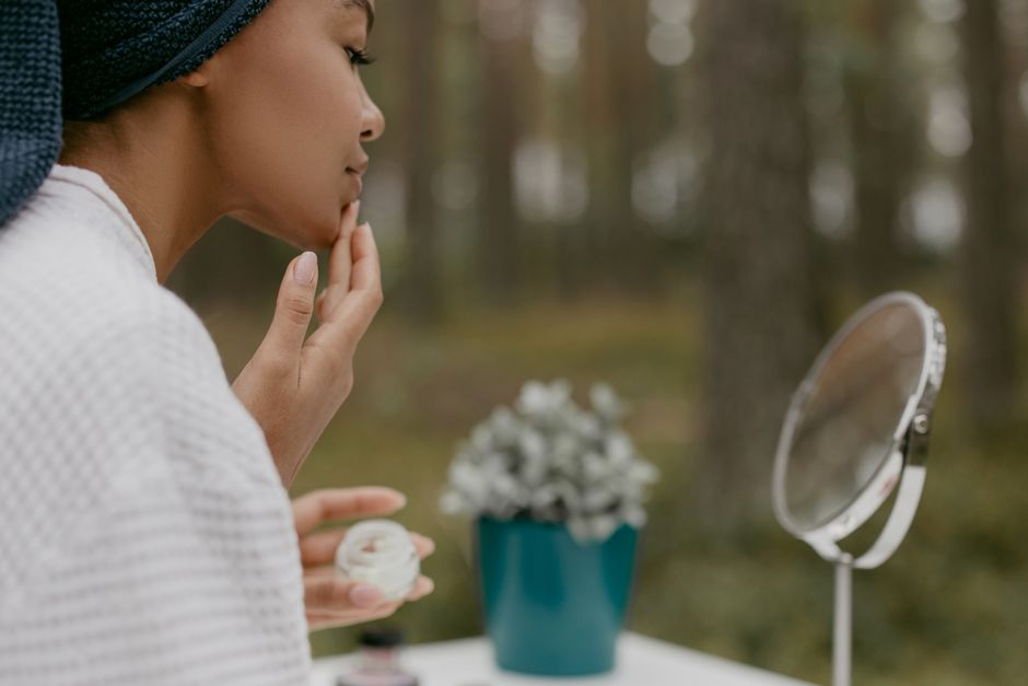 Woman gently applying moisturizer to her face in the morning, focusing on a healthy skin barrier.