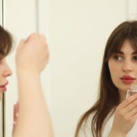 Adult woman gently applying a small amount of retinol serum to her face, emphasizing a careful beginner approach to skincare.
