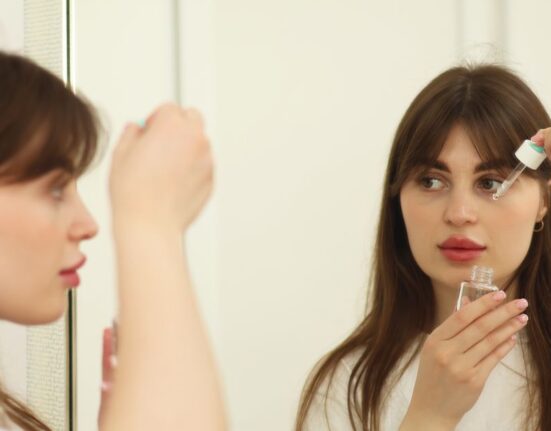 Adult woman gently applying a small amount of retinol serum to her face, emphasizing a careful beginner approach to skincare.