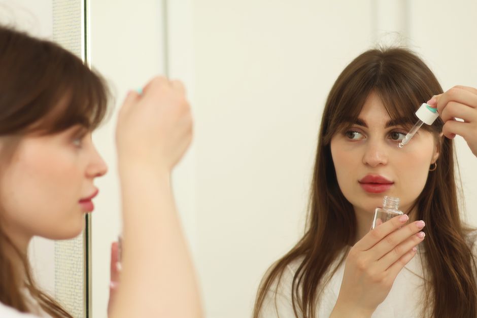 Adult woman gently applying a small amount of retinol serum to her face, emphasizing a careful beginner approach to skincare.