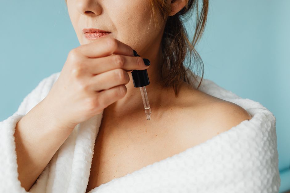 A person with clear, healthy-looking skin gently applying a translucent serum to their face, illustrating the universal appeal and efficacy of hydrating skincare products.