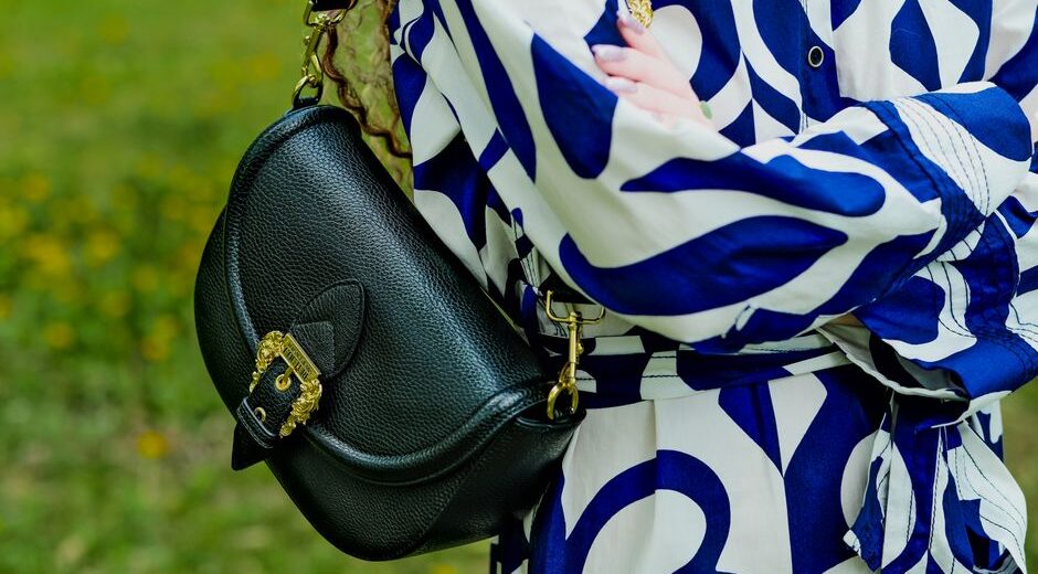 A woman carefully wiping down her brown leather crossbody bag with a soft cloth, demonstrating gentle cleaning.