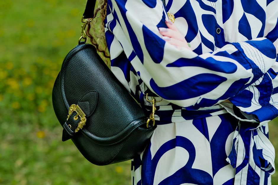 A woman carefully wiping down her brown leather crossbody bag with a soft cloth, demonstrating gentle cleaning.
