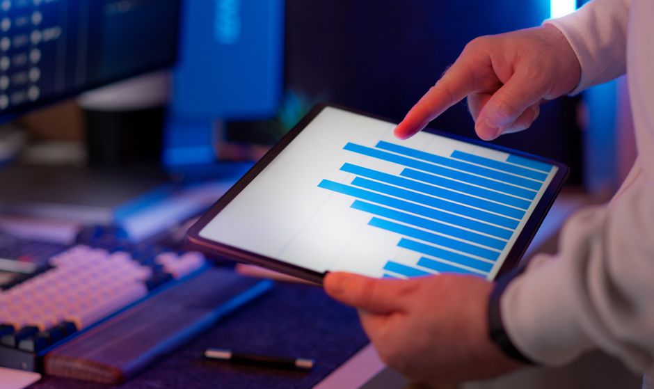 A woman intently reviewing her bank statements and budgeting app on a tablet, with a calculator and coffee nearby, symbolizing financial vigilance.
