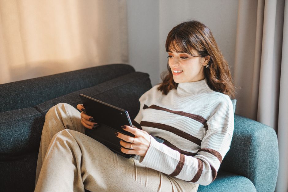 A woman watching a streaming service on a tablet, with a blurred world map in the background to represent overcoming geo-restrictions with a VPN.