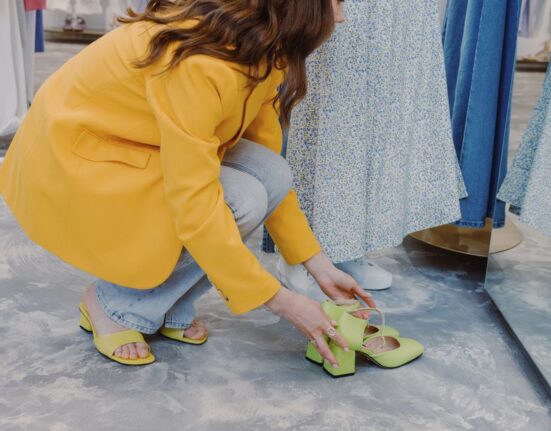 Woman sitting on a bench, trying on a pair of comfortable brown loafers in a shoe store, checking the fit.