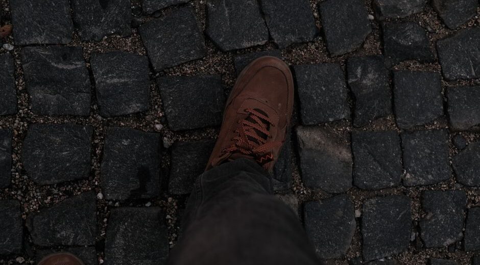 A woman wearing comfortable sneakers walks happily on a historic European cobblestone street, looking relaxed and comfortable.