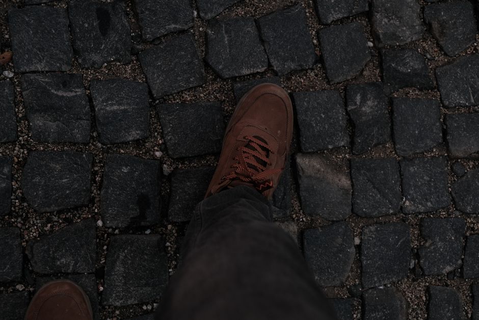 A woman wearing comfortable sneakers walks happily on a historic European cobblestone street, looking relaxed and comfortable.