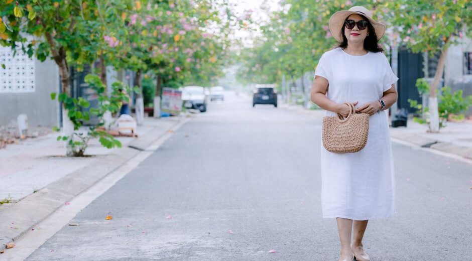 Woman elegantly walking through a sunny European street in a loose-fitting linen dress, showcasing breathable summer fashion.
