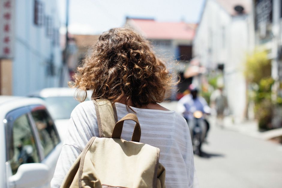 A woman confidently walking through a European city street, carrying a well-fitted ergonomic backpack, demonstrating comfortable weight distribution.
