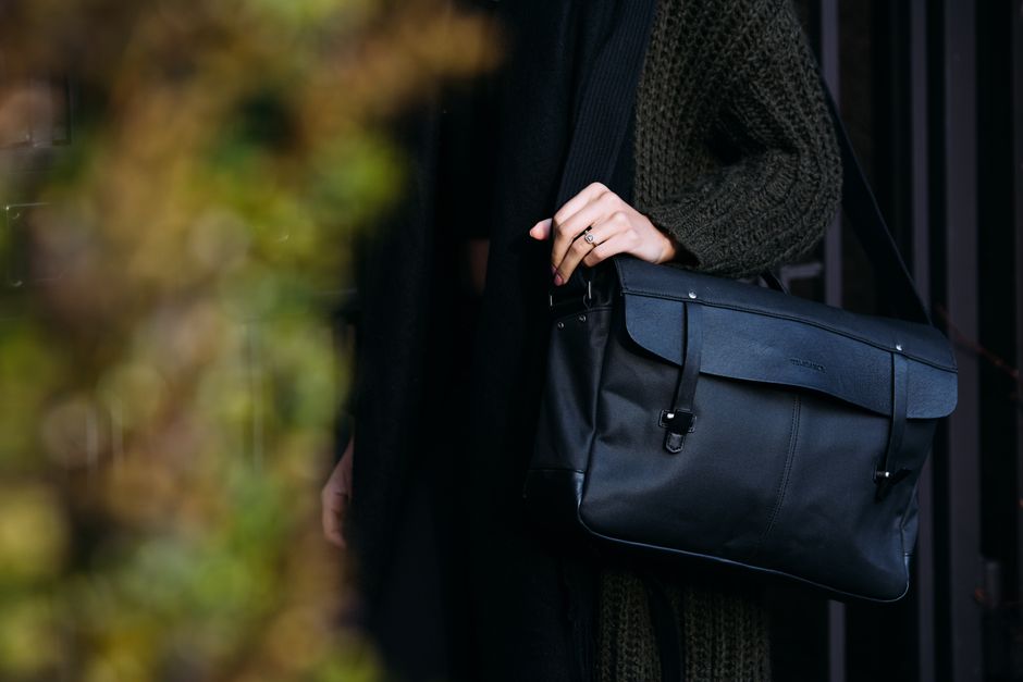A person walking through a historic European city street, carrying a stylish and functional messenger bag, showcasing comfortable carry and accessibility.